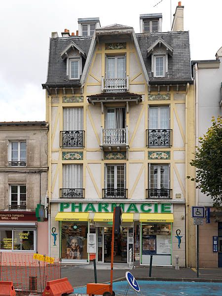 Ablon-sur-Seine, immeuble, 42 rue du Bac. Vue de la façade en 2011. Mur gouttereau à trois travées, la travée principale est soulignée par des balcons en bois et surmontée d'un pignon dont le toit est saillant. Le décor est composé de faux pans de bois en ciment (ou faux colombages), et de carreaux de céramique au-dessus des linteaux des fenêtres figurant un décor végétal.