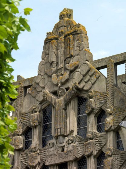Sculpture basse de la façade de l'église. On y voit le Cardinal Mercier. Au dessus Jeannne d'Arc et Saint-Michel, des anges portent les blasons des deux nations soeurs. ; Sculpture de la façade de l'église. On y voit la Trinité.