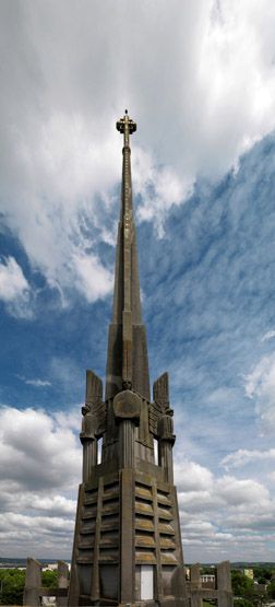 La flèche de l'église. On y voit la croix ainsi que les anges sculptés.