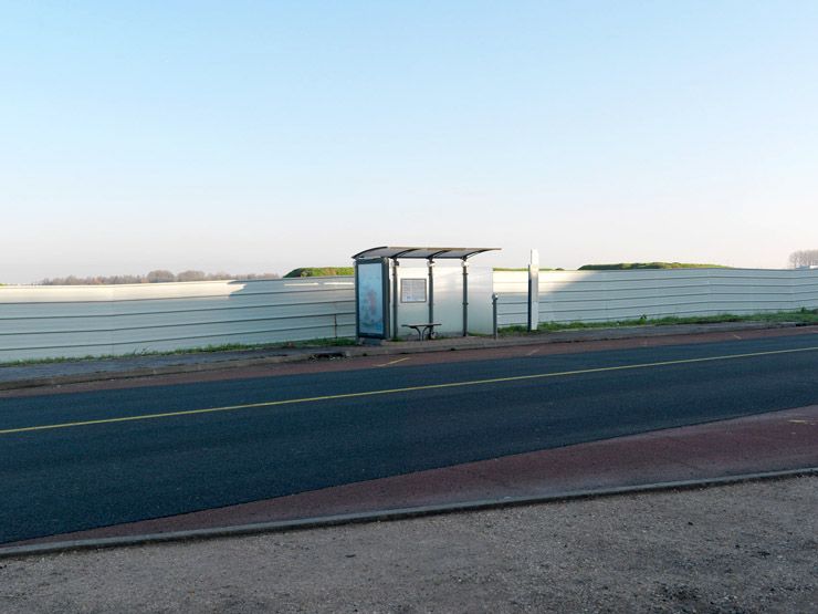 Orsay, route Départementale 118. Vue d'un abri-bus sur la route départementale 128 avec en arrière plan les palissades du chantier Agro ParisTech.