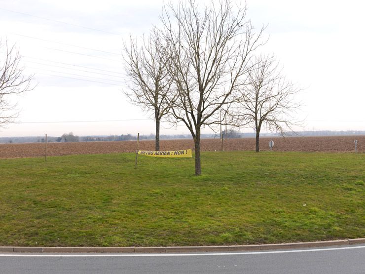 Villiers-le-Bâcle, route de Châteaufort. Vue des champs au nord de la commune. Au premier plan, un rond-point avec une banderolle dénonçant l'arrivée du métro aérien.