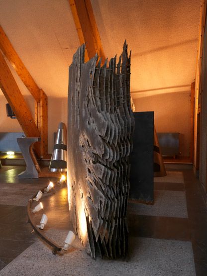 Vue de profil du paravent Le Cosmos, montrant la succession des dix feuilles métalliques assemblées formant le volume de la sculpture. A droite, la porte permettant d'entrer dans le volume.