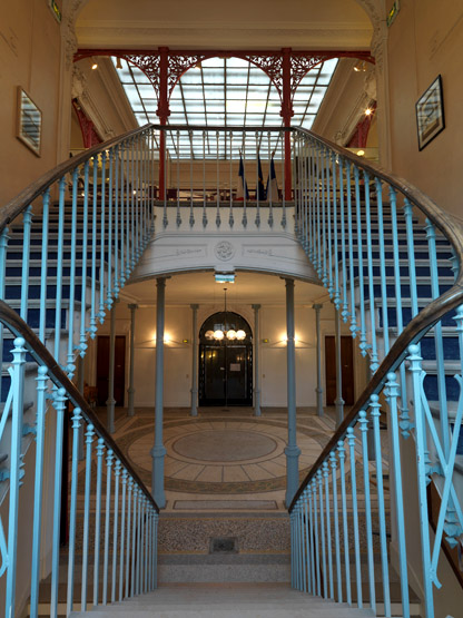 Vue de l'escalier tournant à trois volées droites. Il comporte une volée double à montées parallèles, puis une volée centrale puis une volée double à montées parallèles.