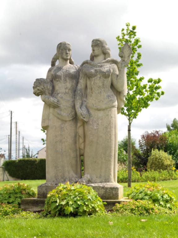 Vue de face du groupe sculpté. A gauche Gassicourt se reconnaît à sa gerbe de blé. A droite, Mantes tient les armoiries composées d'une demi fleur de lys et demi feuille de chêne.
