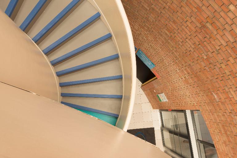 Vue en contre-plongée de l'escalier en vis du hall d'accueil.