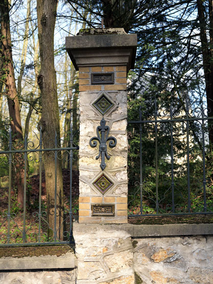 Détail du mur de clôture de la villa : pilier à décor de grès cérame et fer d'ancrage.