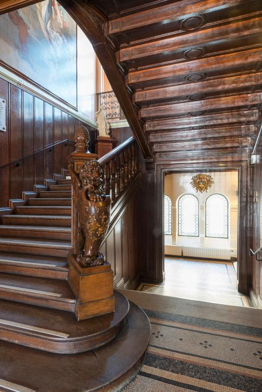 Le départ de l'escalier d'honneur, avec une sculpture de chimère tenant l'écu aux armes de la ville, oeuvre du sculpteur Maximilien Bourgeois.