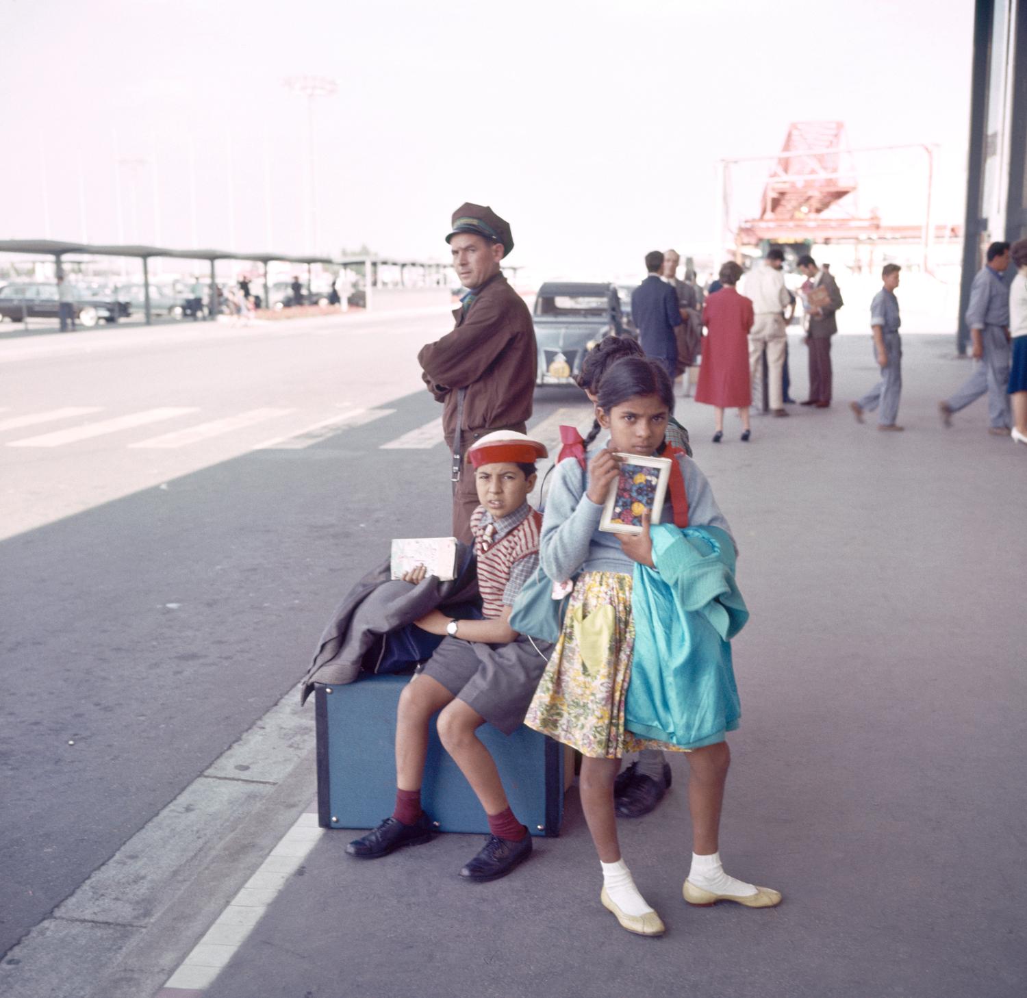 1961, jeunes passagers attendant un taxi sur le parvis du Grand Hall.