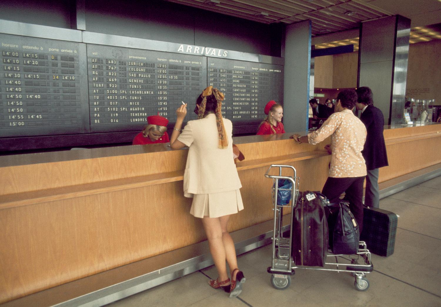 Rez-de-chaussée, passagers devant les comptoirs d'enregistrement de l'Aéroport de Paris.