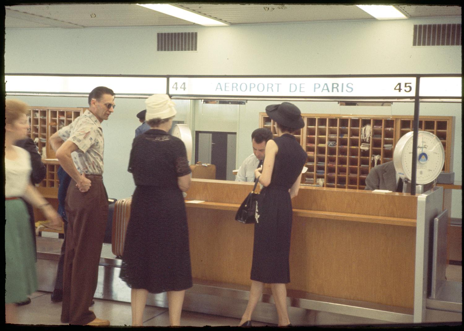 1961, rez-de-chaussée, passagers devant les comptoirs d'enregistrement de l'Aéroport de Paris.