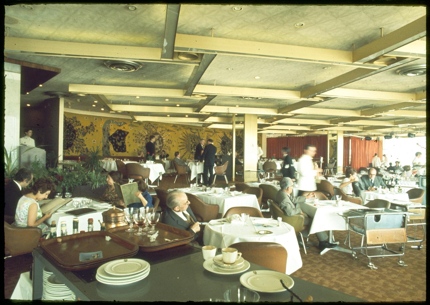 1971, les Trois Soleils, conception des aménagements André Renou et Jean-Pierre Génisset (la Crémaillère), fauteuils Conférence (Eero Saarinen), au fond de la salle la tapisserie de Jean Lurçat qui donne son nom au restaurant, 3ème étage.  ; 1971, les Trois Soleils, conception des aménagements André Renou et Jean-Pierre Génisset (la Crémaillère), au fond de la salle la tapisserie de Jean Lurçat qui donne son nom au restaurant, 3ème étage. 