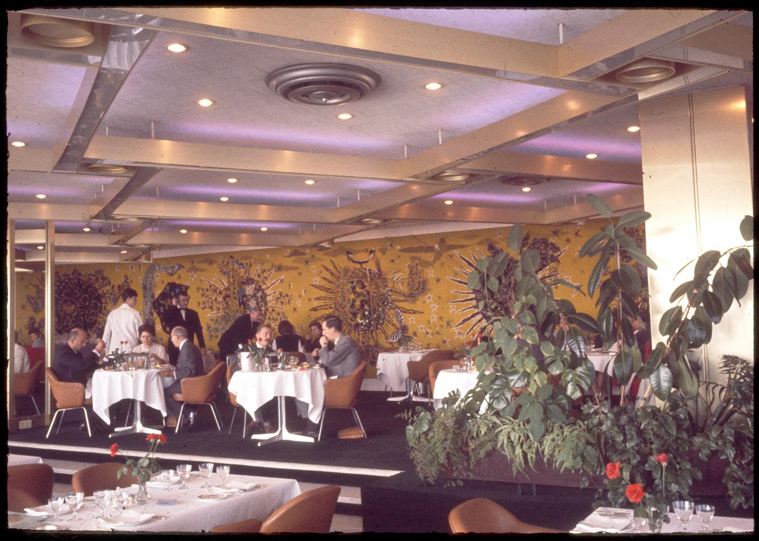 Les Trois Soleils, conception des aménagements André Renou et Jean-Pierre Génisset (la Crémaillère), fauteuils Conférence (Eero Saarinen), au fond de la salle la tapisserie de Jean Lurçat qui donne son nom au restaurant, 3ème étage.  ; Les Trois Soleils, conception des aménagements André Renou et Jean-Pierre Génisset (la Crémaillère), au fond de la salle la tapisserie de Jean Lurçat qui donne son nom au restaurant, 3ème étage. 