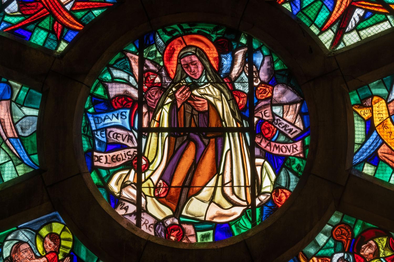 Détail du centre de la rosace, avec Sainte Thérèse de Lisieux. En prière, vêtue de l'habit carmélite, elle est entourée de huit panneaux en forme de pétales. 