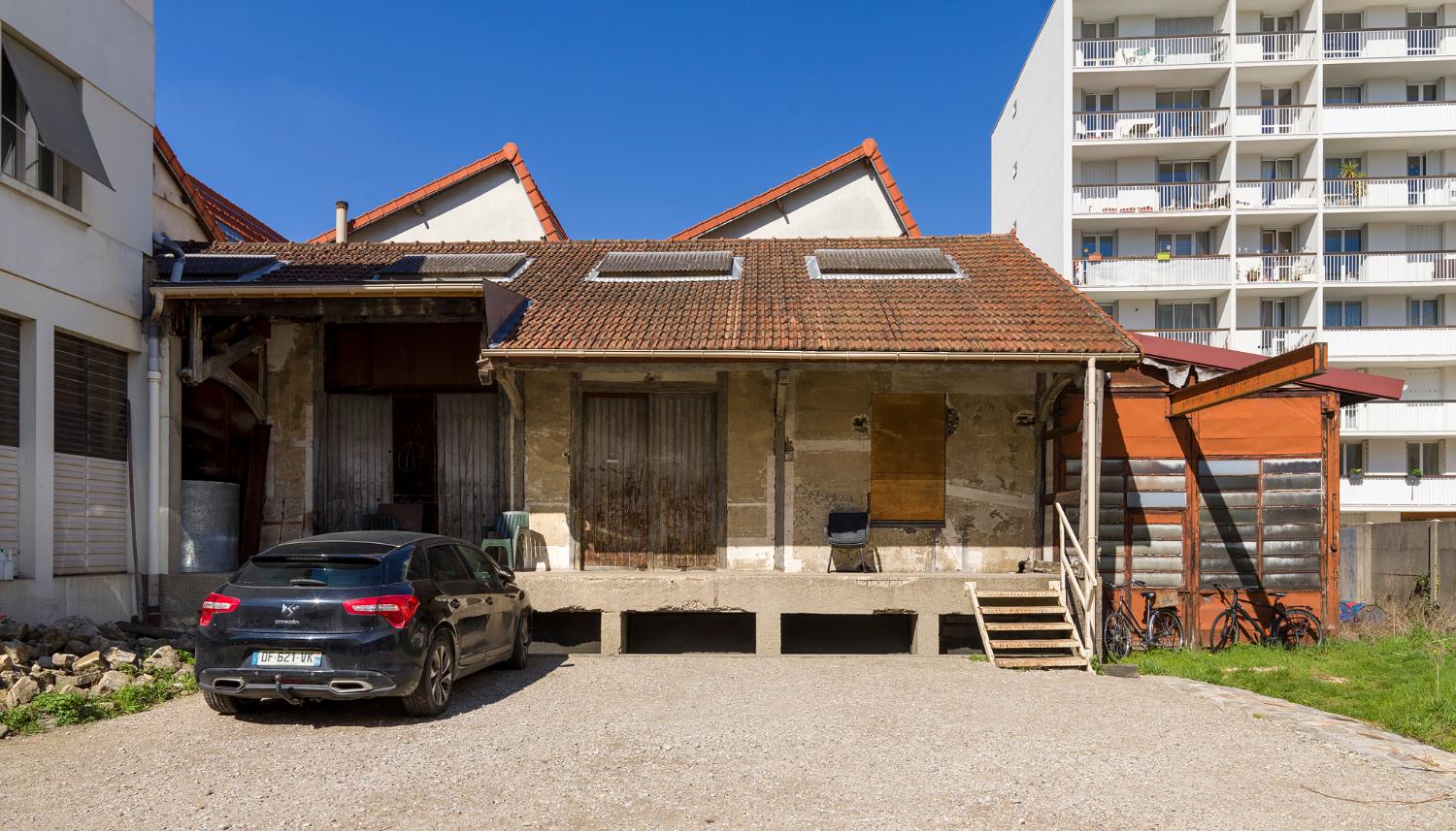 Quai de déchargement. À l’arrière, bâtiment à 3 sheds, dernier lieu de fabrication de la société du Lysol, actuellement atelier de thermoformage et espace de stockage.