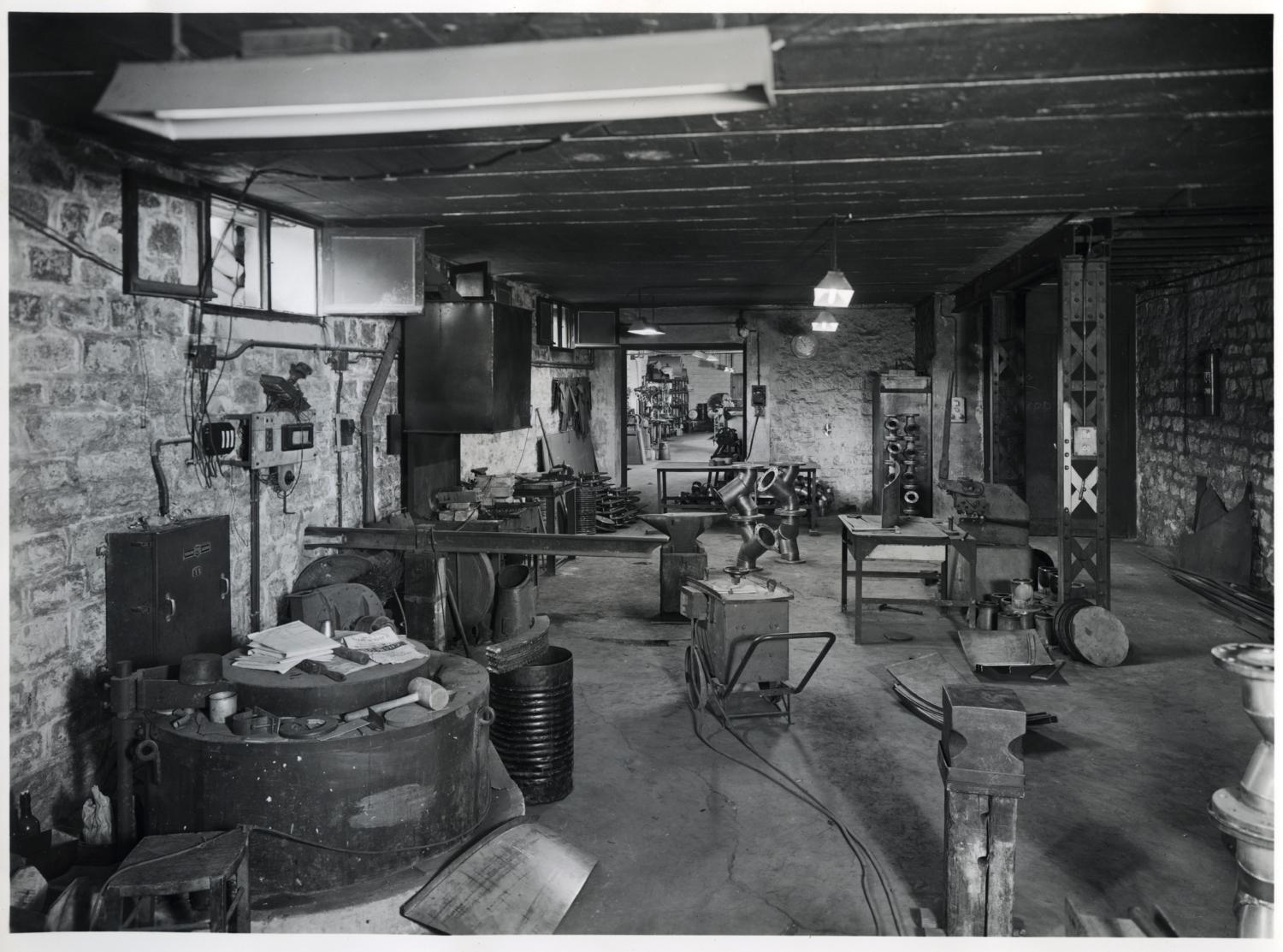 Atelier de chaudronnerie métallique, au sous-sol. Tirage photographique noir et blanc, 18 x 24 cm, années 1950, Studio Louisianne, 152 avenue Danielle Casanova, Ivry-sur-Seine (collection Ateliers de Technochimie). 