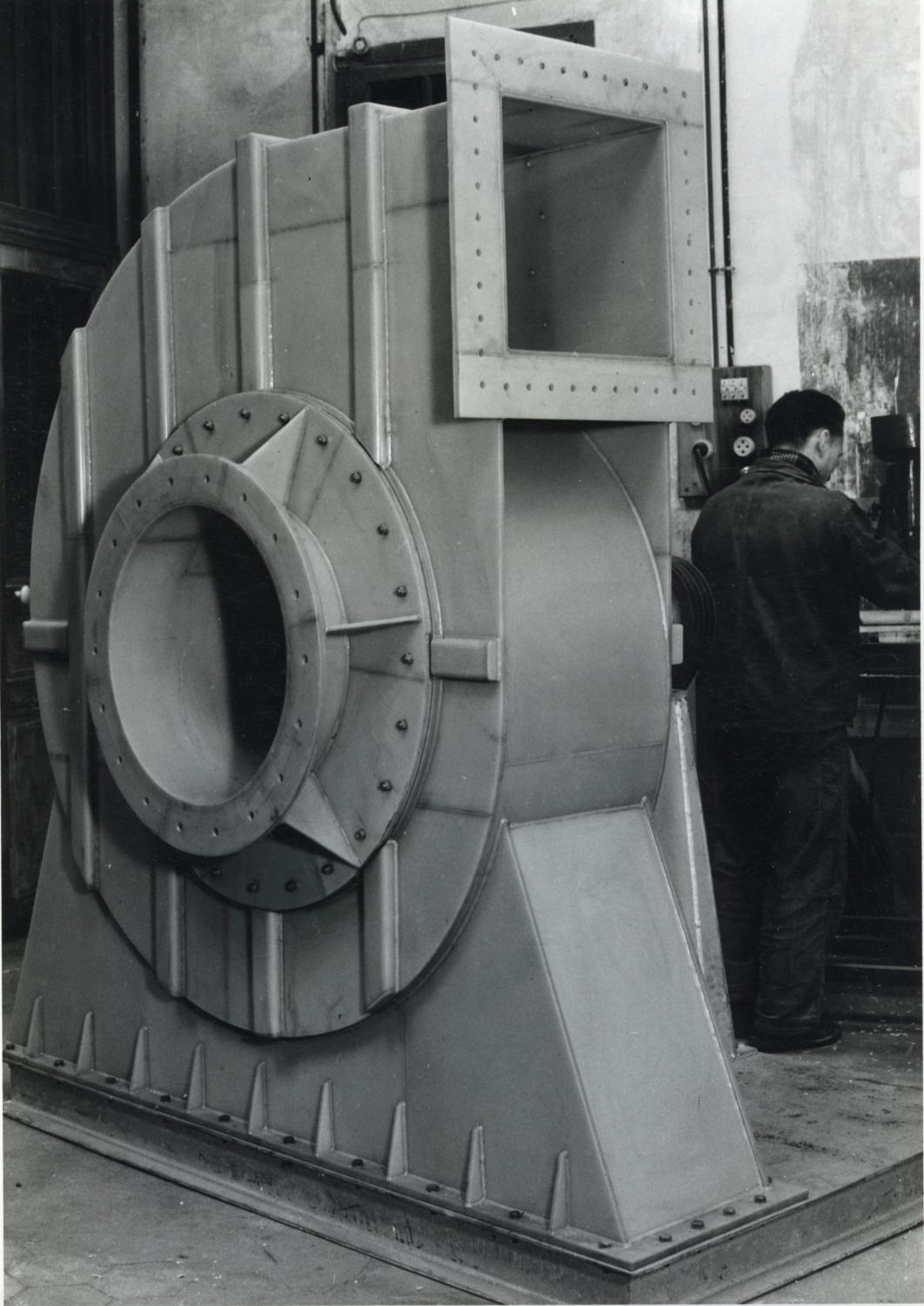 Ventilateur centrifuge pour évacuation de vapeurs en PVC, dans l'atelier de chaudronnerie plastique, au rez-de-chaussée. Tirage photographique noir et blanc, 13 x 18 cm, années 1960, Tirage A. Papillon Photographies, 10 bis rue Frémicourt, Paris 15e (collection Ateliers de Technochimie). 