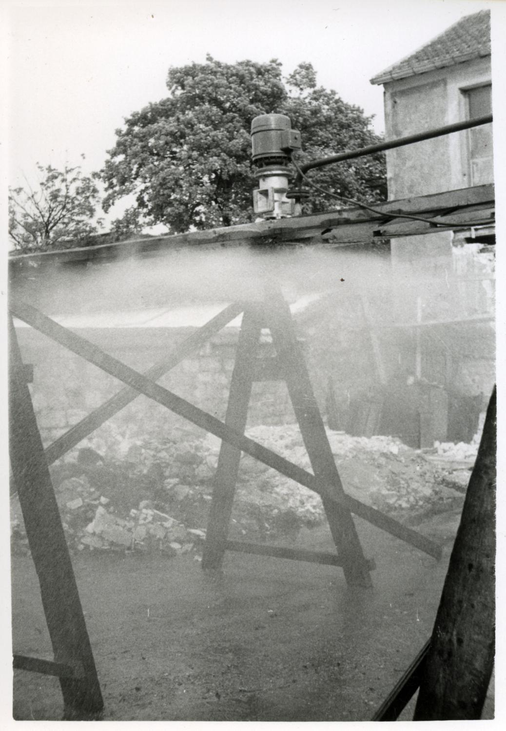 Essai de pulvérisateur pour les installations de fabrication d'acide sulfurique, dans la cour. Tirage photographique noir et blanc, 8 x 11,5 cm, années 1950, sans mention d'auteur (collection Ateliers de Technochimie).