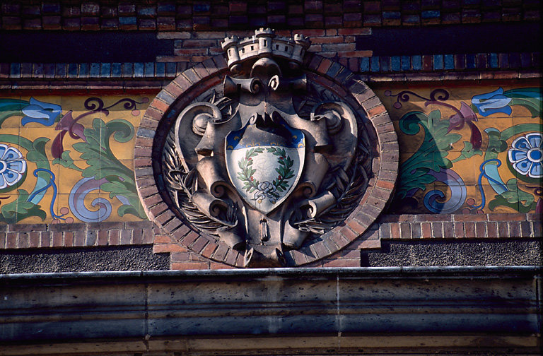 Détail d'une frise en céramique et d'un blason sculpté.
