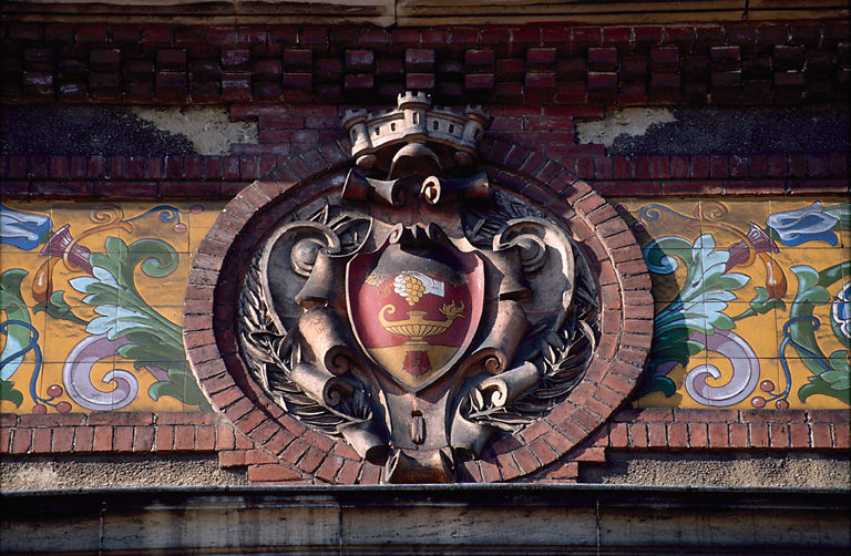 Détail d'une frise en céramique et d'un blason sculpté.