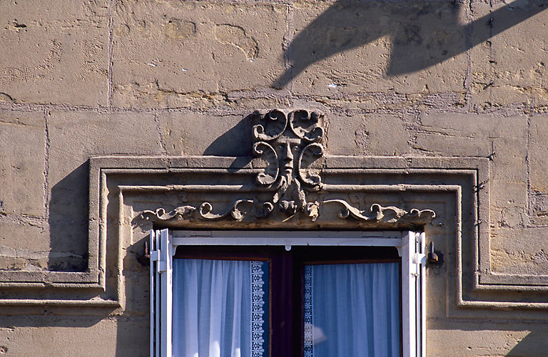 Vue de détail d'une fenêtre et son linteau orné.