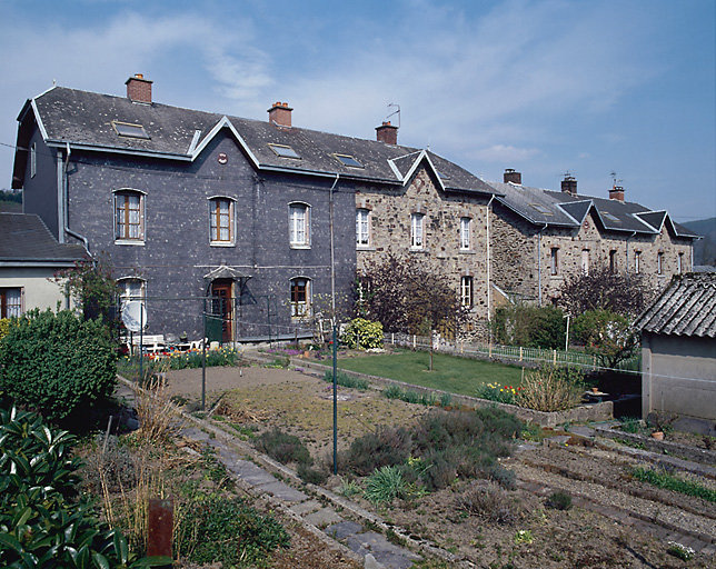 Maisons de la cité en quartzite, à bardage en ardoise, vues de trois-quart gauche.