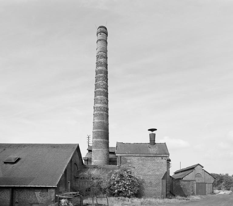 Vue extérieure des bâtiments industriels et de la cheminée d'usine.