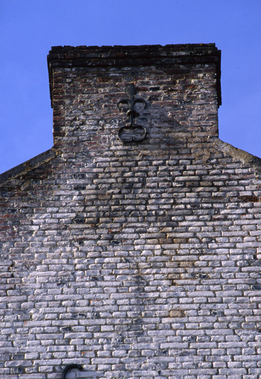 Partie supérieure du pignon oriental du logis, ornée d'un fer d'ancrage en forme de fleur de lys.