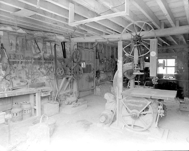 Vue d'ensemble de l'intérieur de l'atelier de charron avec les machines et outils encore en place.
