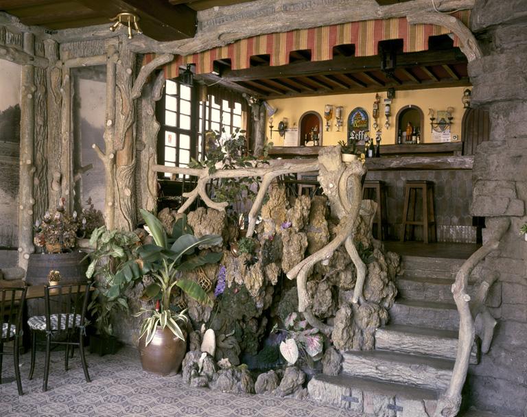 Vue générale de l'intérieur du café, avec, au 1e plan, la fontaine et l'escalier donnant accès au bar.