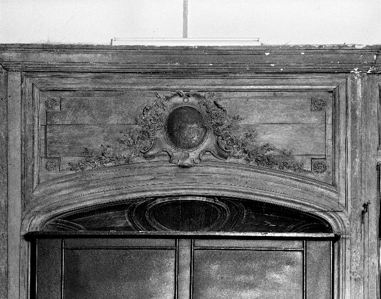 Détail du décor sculpté des lambris situés au-dessus de la grande porte.