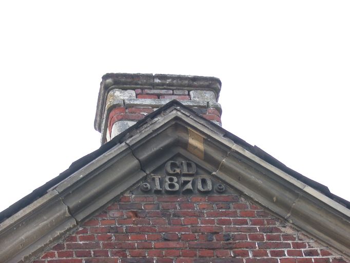 Détail des initiales GD et de la date de 1870 portées sur le pignon ouest du magasin à grains.