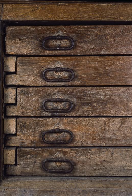 Vue de l'extrémité des tiroirs, avec les poignées ou anneaux de tirage et leur platine.