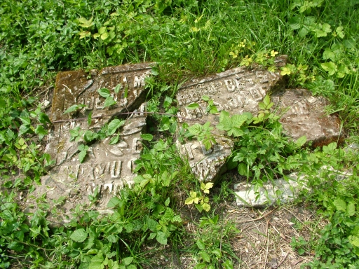 Vue de la plaque rédigée en français, brisée, située à terre.