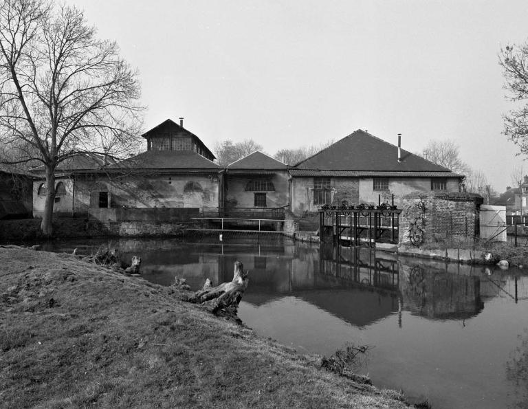Vue générale de l'usine, depuis l'est, avec son canal d'amenée passant sous les ateliers et son canal de décharge avec vannage à droite (état en 1985).