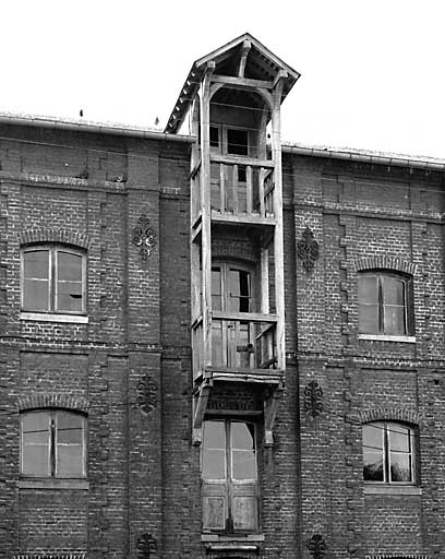 Façade nord-est sur rue, détail des niveaux supérieurs de la travée centrale, balcon en bois à usage de monte-charge.