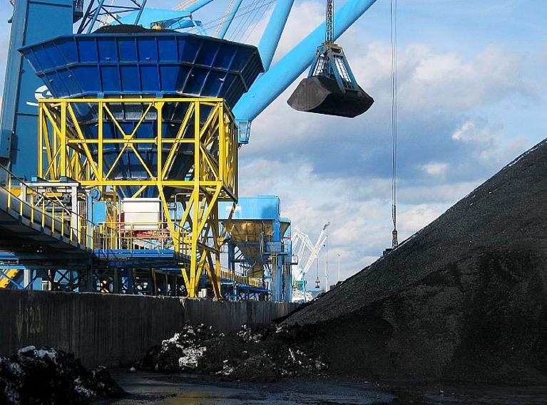 Grue déchargeant le charbon dans une trémie installée sur un convoyeur à bandes.