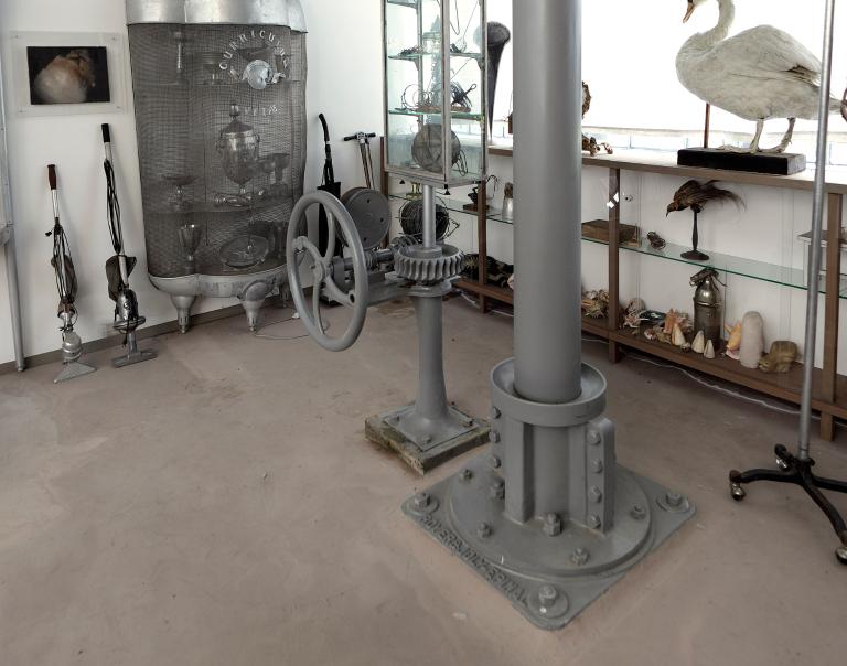 Vue intérieure du bâtiment de la turbine, volant de commande manuelle et axe de transmission.