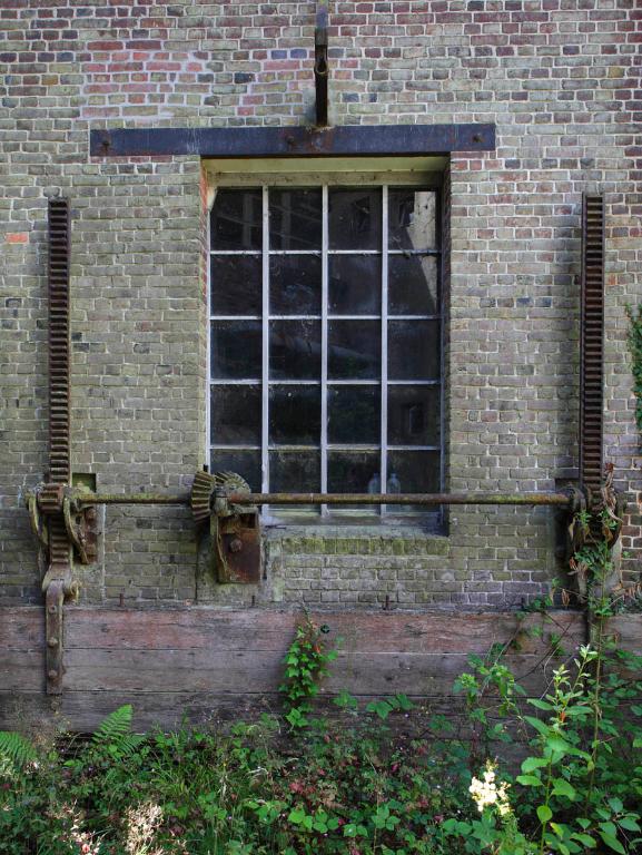 Détail de la façade postérieure de la filature reconstruite en 1950 et vannages sur le canal d'alimentation passant sous la filature.