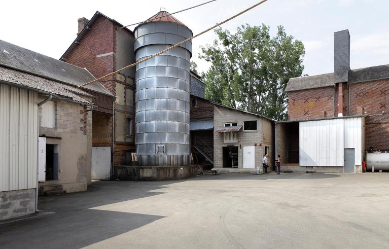 Vue depuis la cour intérieure du site : au centre la façade postérieure du moulin primitif avec silo métallique.