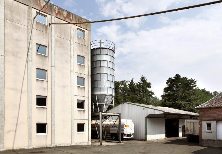 Vue partielle de la minoterie moderne avec silo métallique et remise. ; Minoterie Delafosse, Romilly-sur-Andelle.
