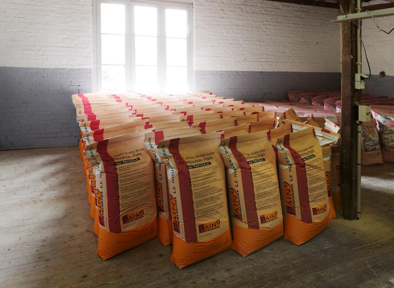 Vue intérieure du moulin primitif : salle d'ensachage et de pesée, sacs de farine prêts à la vente.
