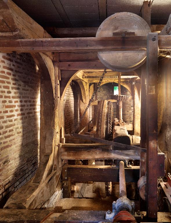 Vue intérieure du moulin : beffroi, engrenage et axe de transmission.
