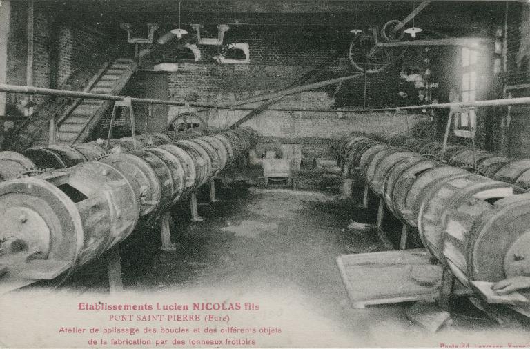 Etablissements Lucien Nicolas fils. Atelier de polissage des boucles et des différents objets de la fabrication par des tonneaux frottoirs.- Carte postale, photo Ed. Lavergne, Vernon, vers 1920 (Collection particulière).