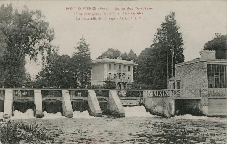 Usine des Terrasses où se fabriquent les célèbres Tirs Euréka. La passerelle du barrage - Au fond et la villa [du PDG].- Carte postale, vers 1930 (Collection particulière).