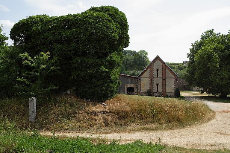 Vue des vestiges du bâtiment de la turbine envahi de végétation (au premier plan) et de la grange (au second plan).