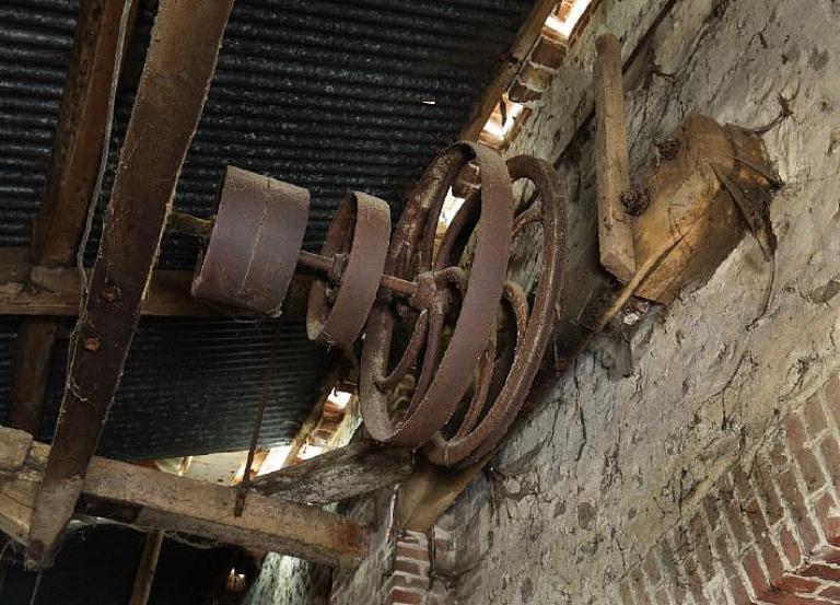 Vue intérieur de l'annexe de la grange, détail d'un arbre de transmission de l'énergie produite par la turbine.