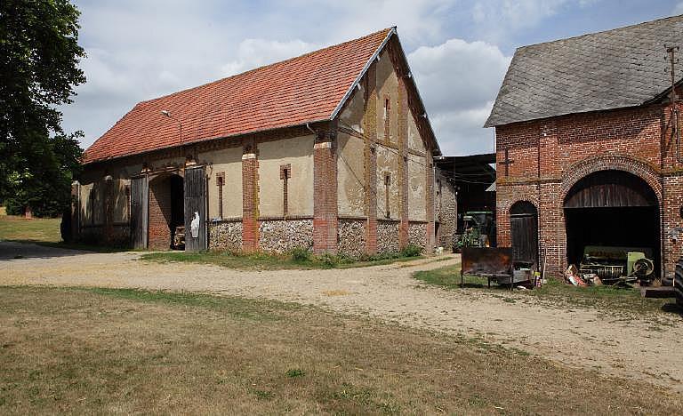 Vue générale de la grange et vue partielle de la remise depuis la cour de la ferme.