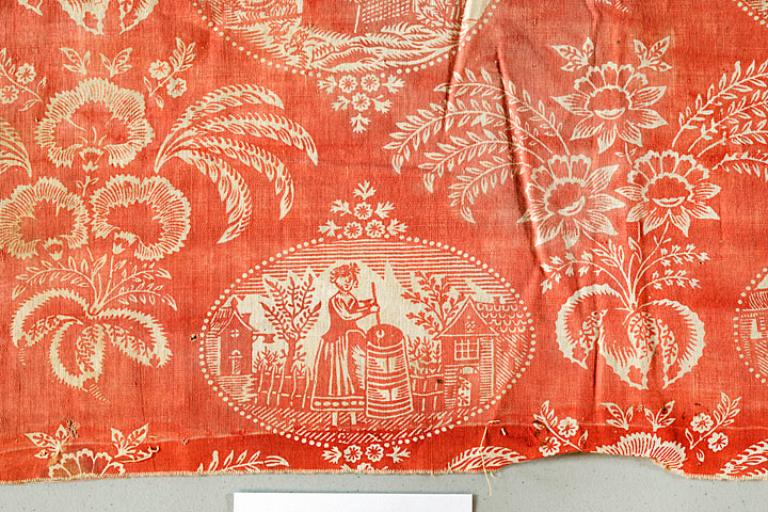 Tissu, coton imprimé, scène de la vie rurale, femme avec baratte à beurre, détail, camaïeurouge, début XIXe siècle (AM. Lyons-la-Forêt).