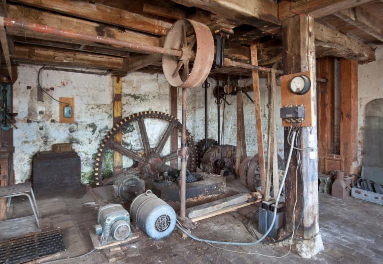 Vue intérieure de la minoterie, rez-de-chaussée, engrenage et système de transmission de l'énergie.