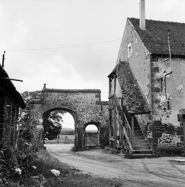 Vue d'ensemble du portail d'entrée des communs et escalier de bois du logis.